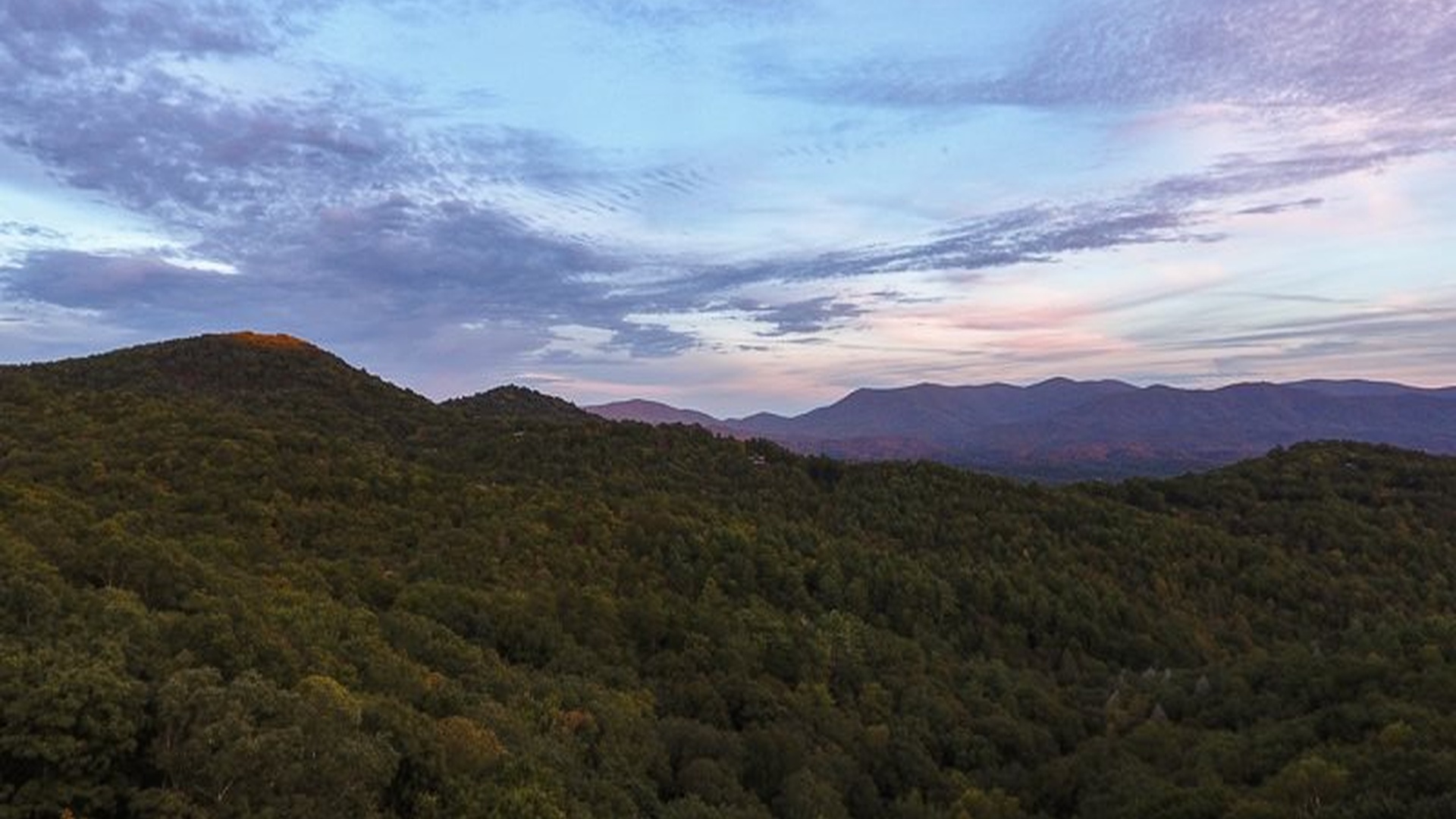 Summer mountain views with soft greens and layered ridges.